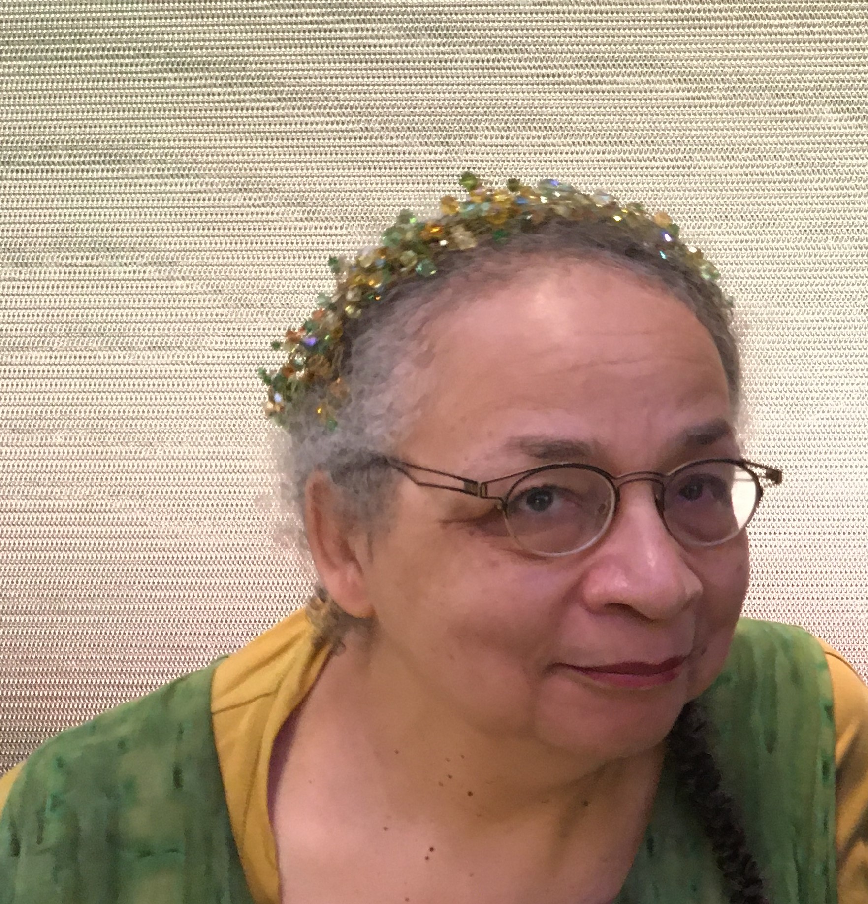 Close-up of the author wearing a beaded tiara and a green vest over a yellow shirt