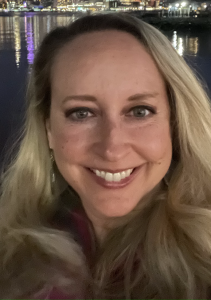 Close-up of the author smiling against a night shot of water