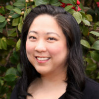 Close-up of the author smiling in front of a background of green leaves