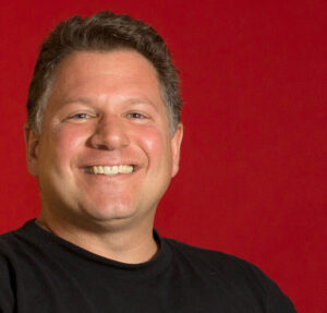 A headshot of the author against a red background.